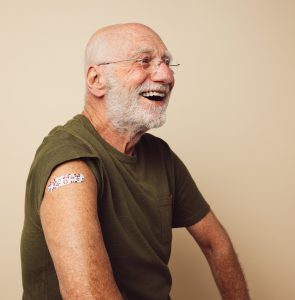 Happy older man sporting a band aid where he's received a vaccination